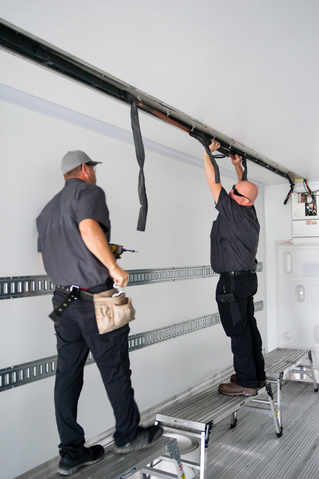 Two Crosspoint Power and Refrigeration technicians working on a carrier multi temp trailer