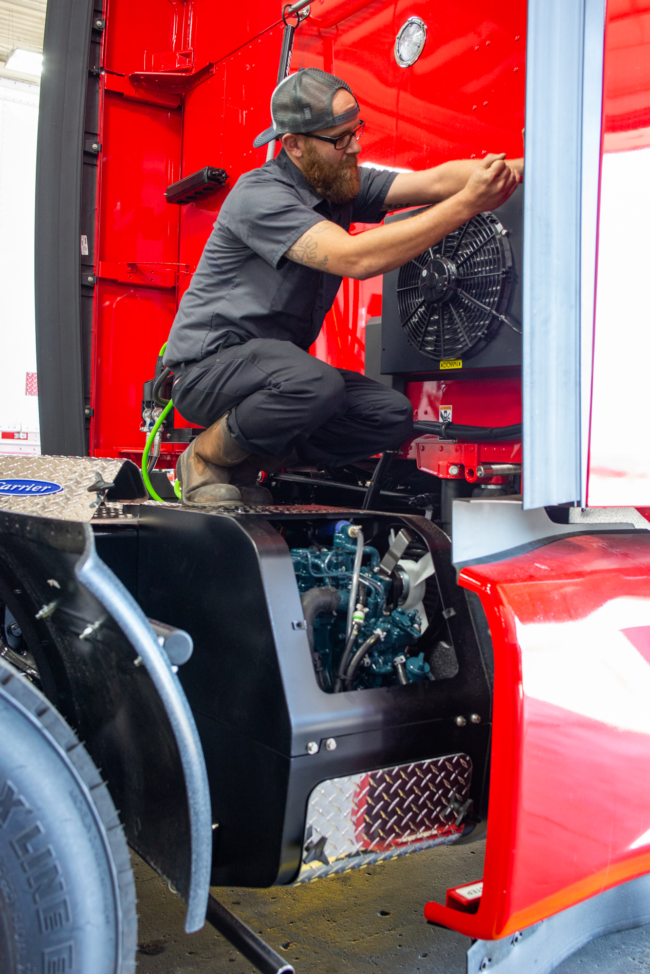 Crosspoint Power and Refrigeration technician working on a Carrier APU on a red truck