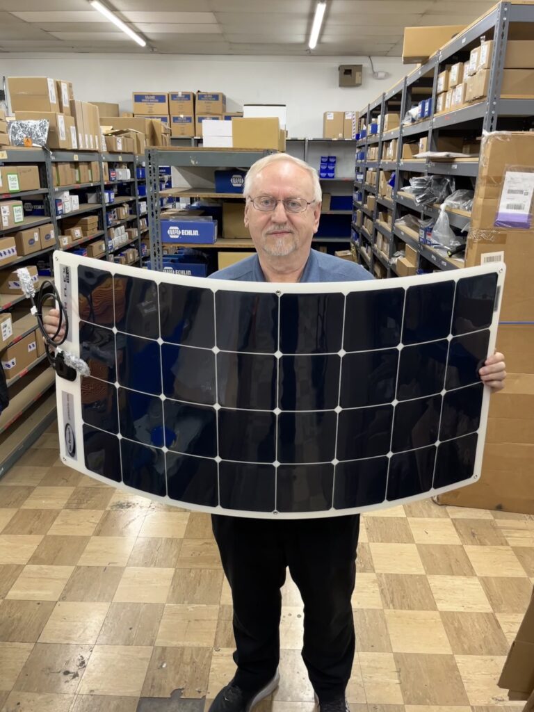 A man holding up a curved solar panel. 