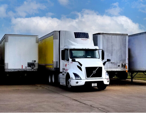 A semi truck with a solar panel mounted on the fairing. 